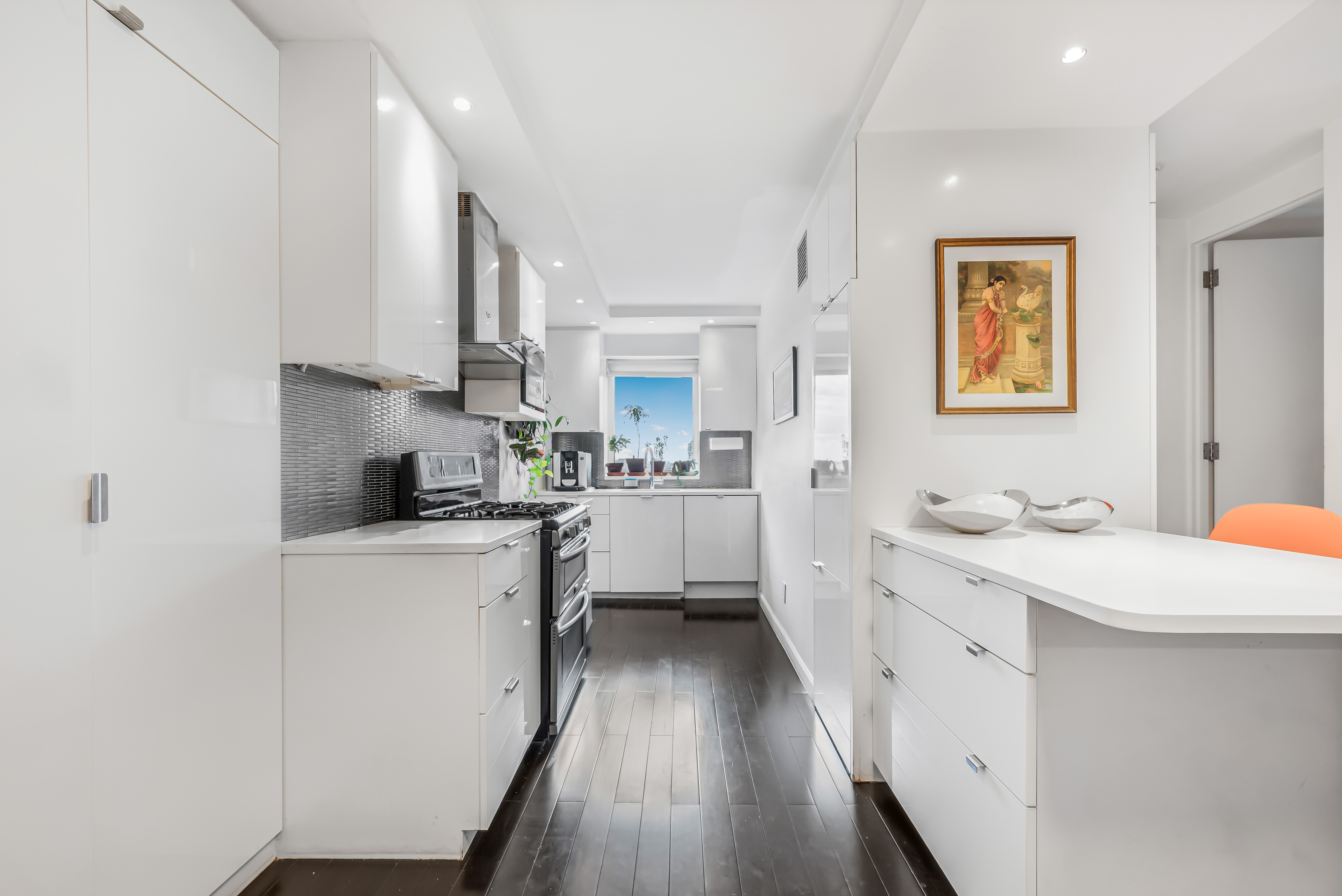 520 East 76th Street, Unit 10H Manhattan, NY 10021 - Photo 2 of 20 a kitchen with stainless steel appliances sink stove refrigerator and white cabinets with wooden floor