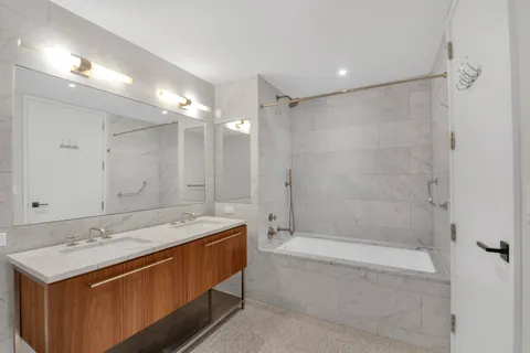 a bathroom with a bathtub shower sink vanity and mirror
