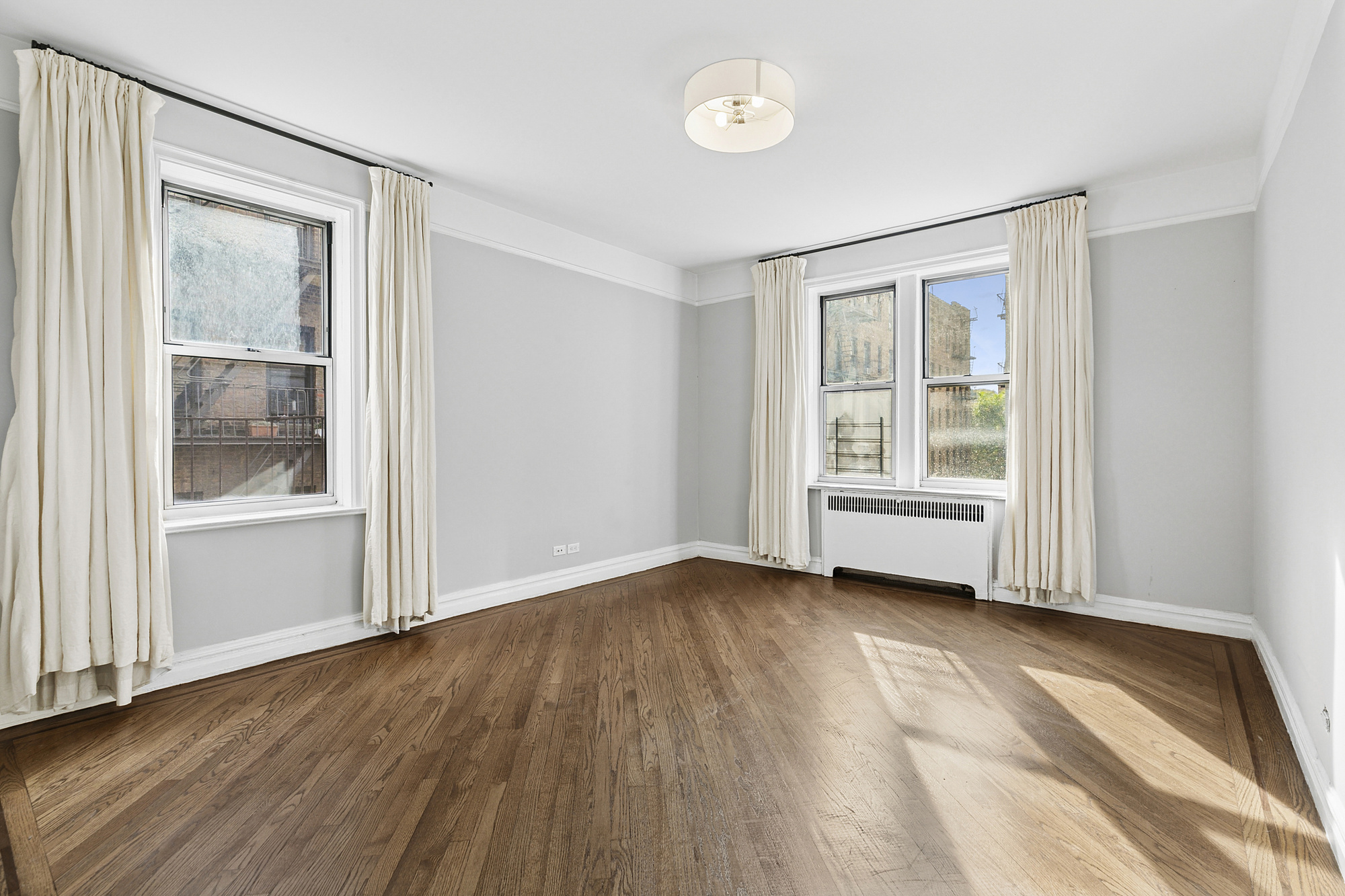 680 West 204th Street, Unit 3E Manhattan, NY 10034 - Photo 4 of 7 an empty room with wooden floor and windows