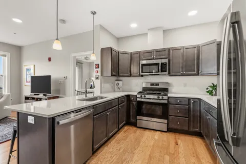 a kitchen with stainless steel appliances a stove a sink a refrigerator a microwave a sink and a refrigerator