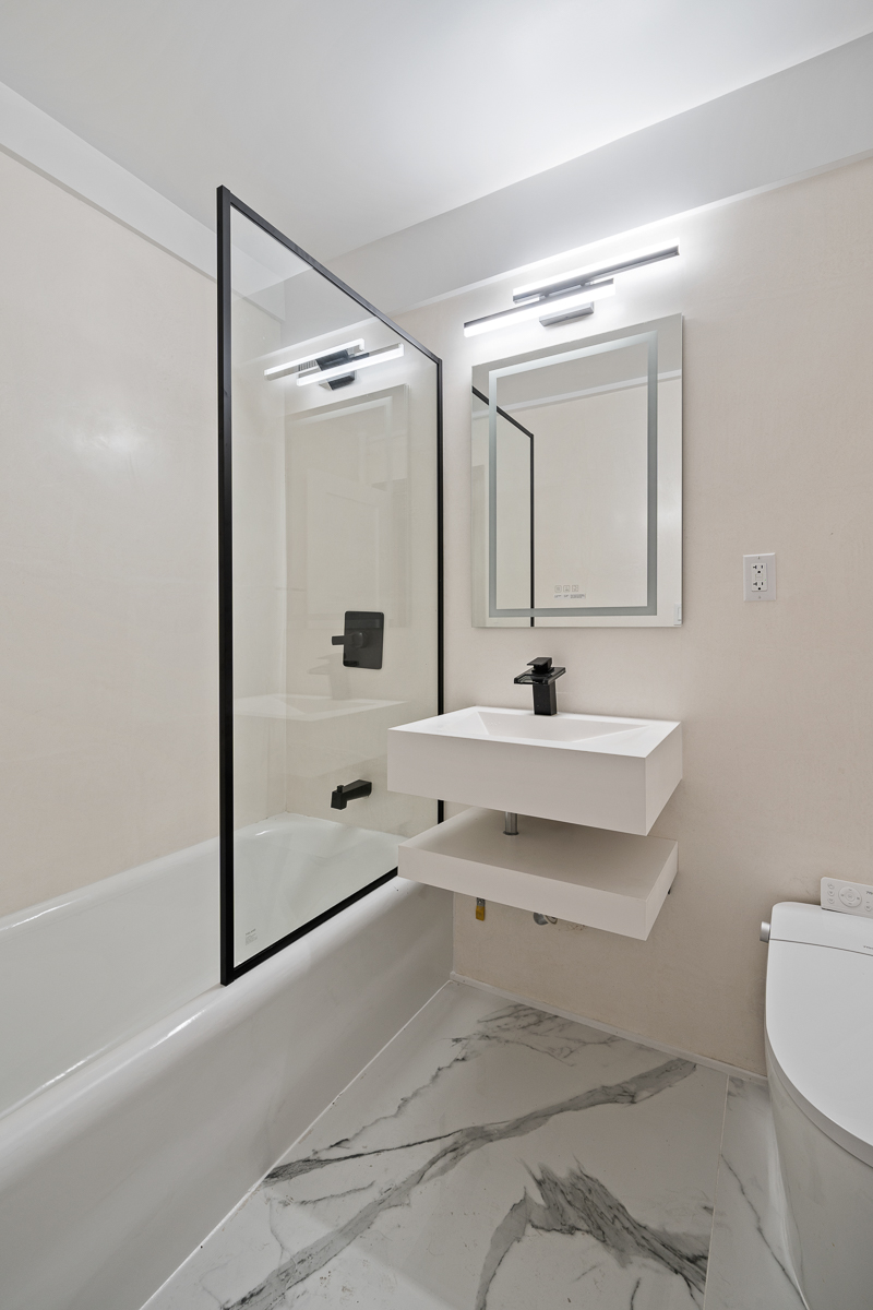 433 West 34th Street, Unit 4K Manhattan, NY 10001 - Photo 5 of 10 a bathroom with a bathtub shower sink vanity and toilet