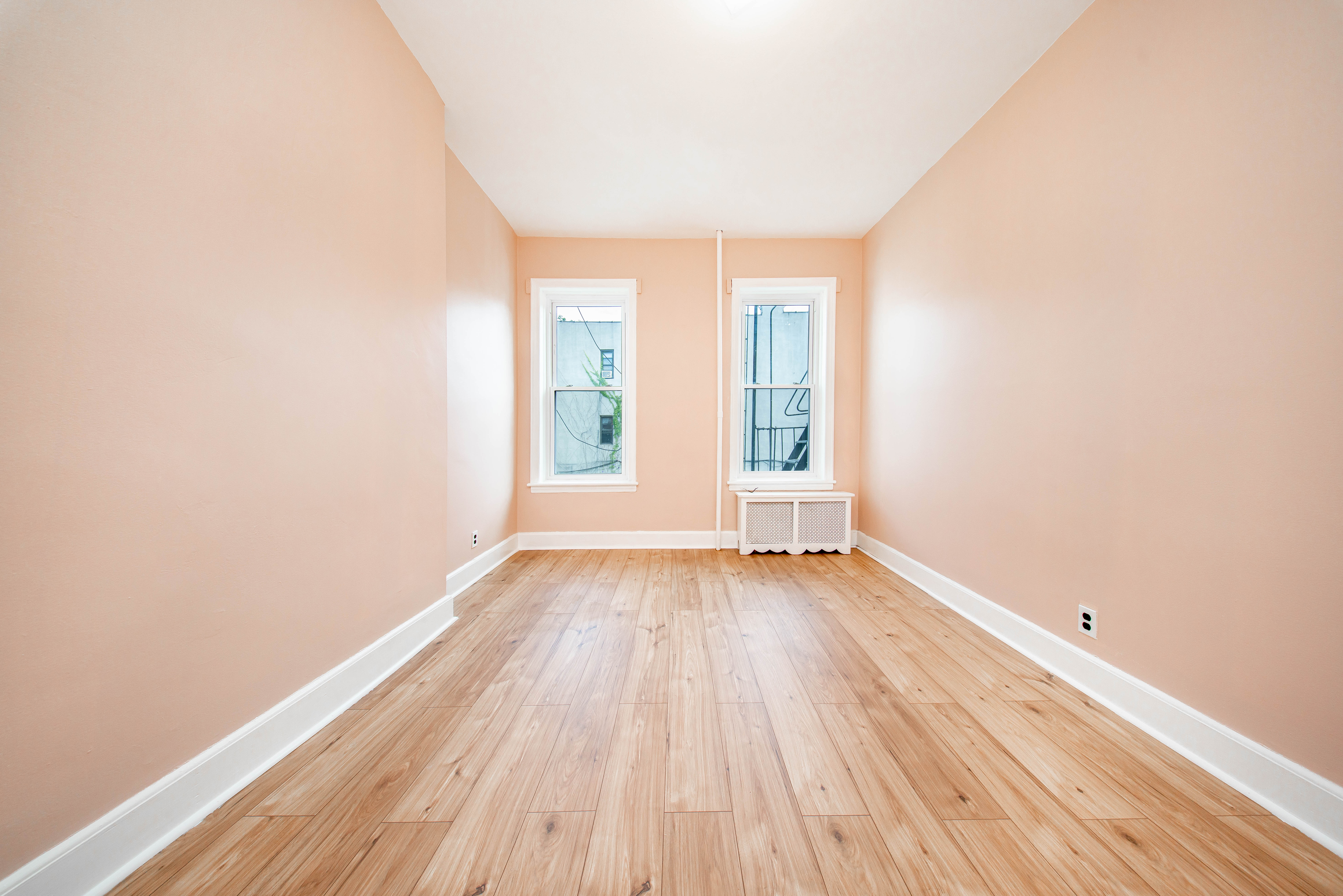 22-17 Astoria Boulevard, Unit 2W Queens, NY 11102 - Photo 8 of 10 an empty room with wooden floor and windows
