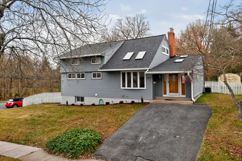 a view of the house with a big yard and large tree
