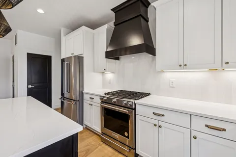a kitchen with stainless steel appliances white cabinets and a stove top oven