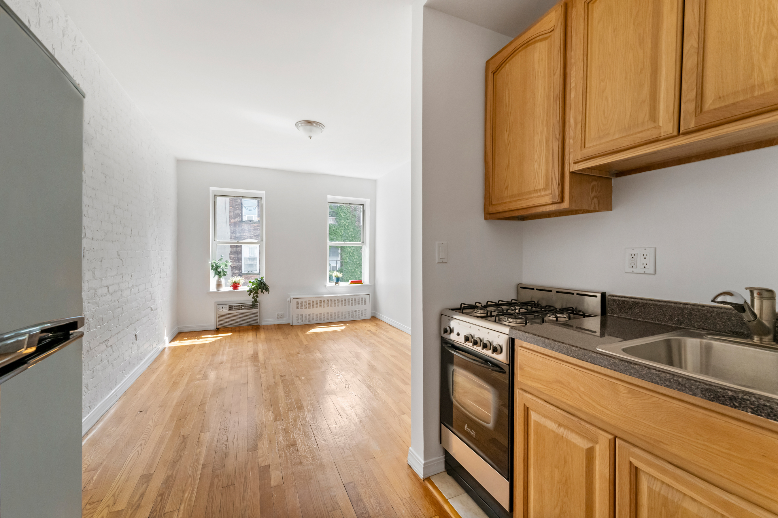 482 East 74th Street, Unit 5C Manhattan, NY 10021 - Photo 4 of 8 a kitchen with granite countertop a sink a stove and cabinets