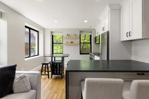 a kitchen with stainless steel appliances granite countertop a table chairs in it and a window