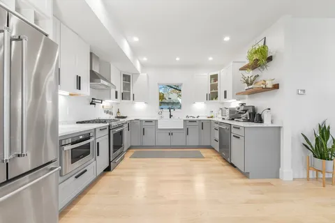 a kitchen with white cabinets stainless steel appliances and a potted plant