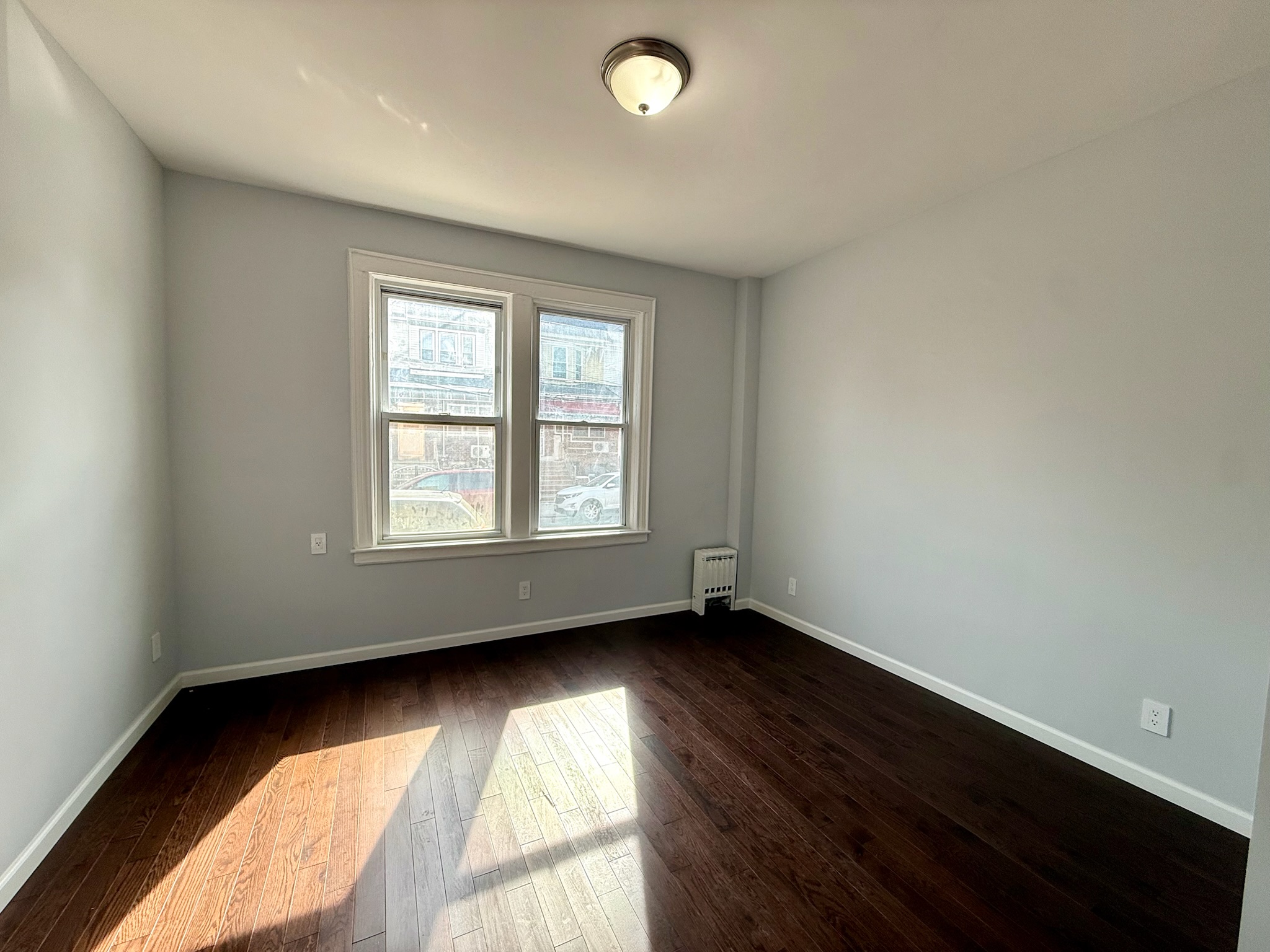 1675 85th Street, Unit 1F Brooklyn, NY 11214 - Photo 2 of 7 an empty room with wooden floor and windows