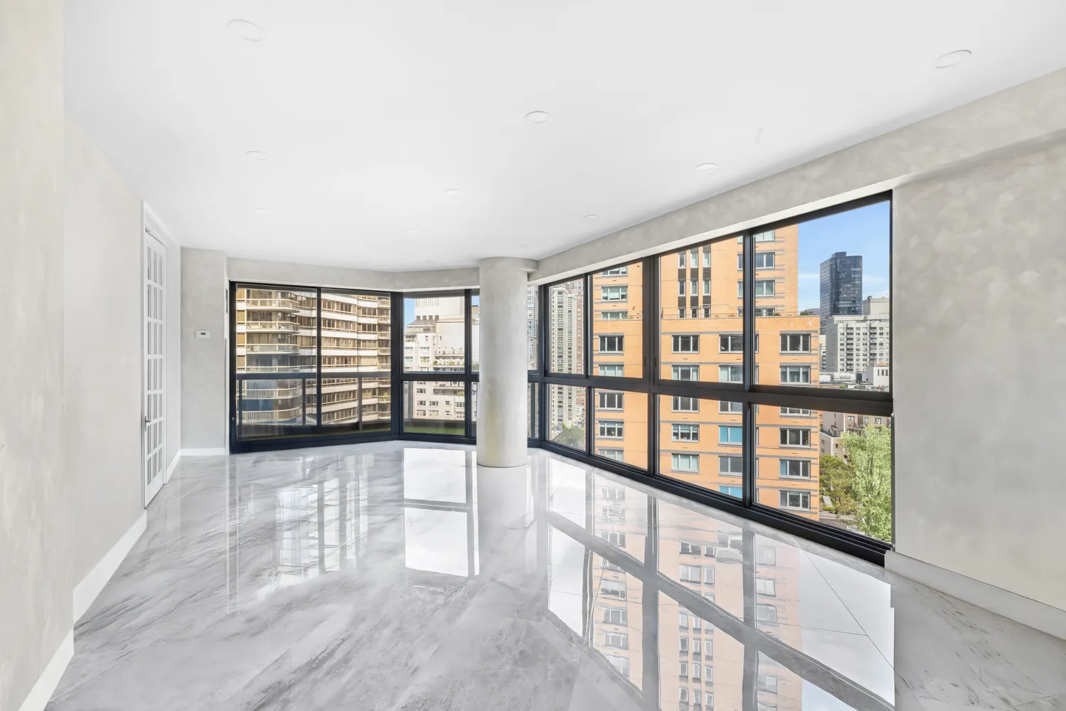 a view of an empty room with wooden floor and fan