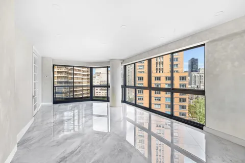 a view of an empty room with wooden floor and fan