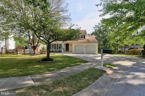 a view of a house with a yard and large trees