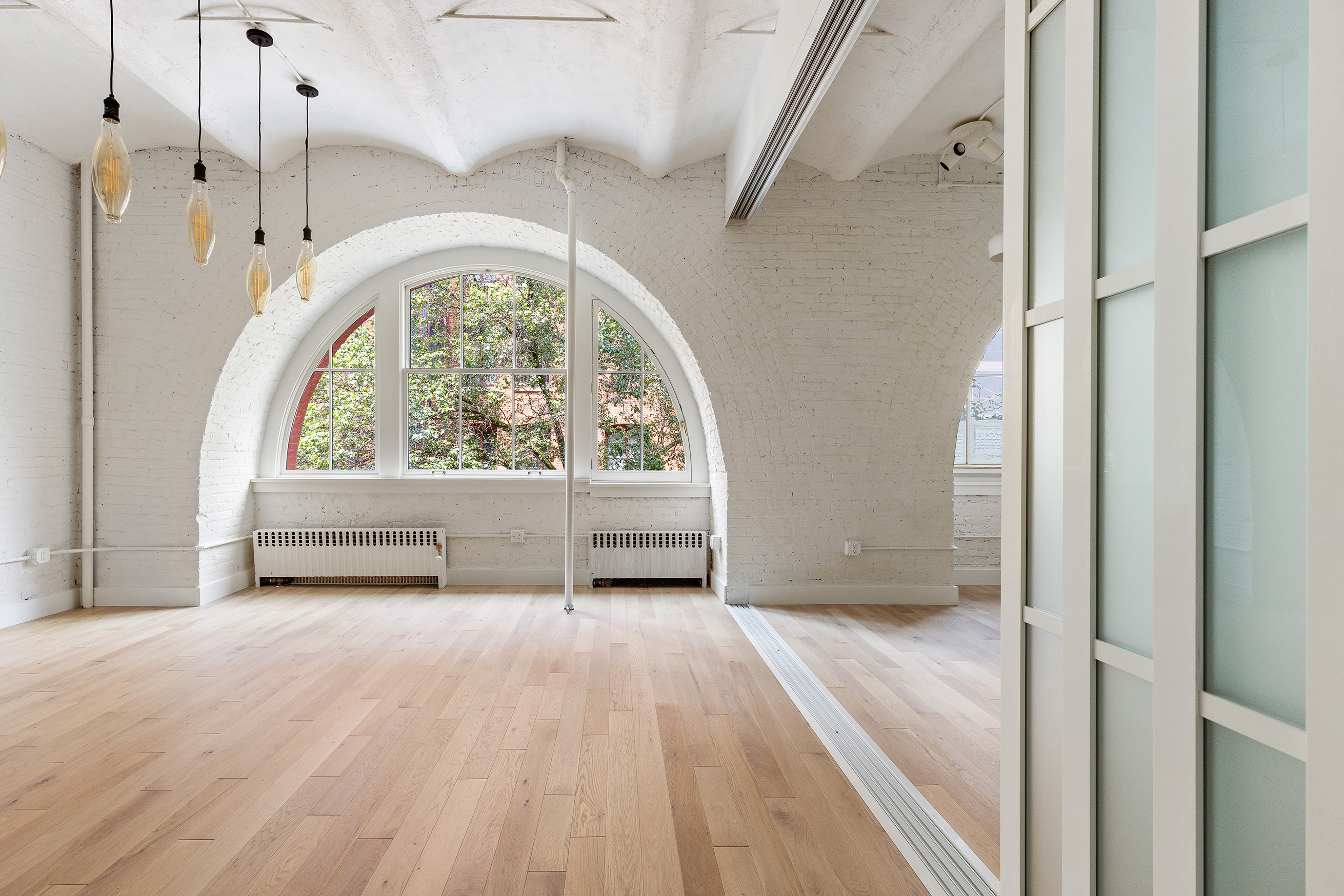 a view of an empty room with a window and wooden floor