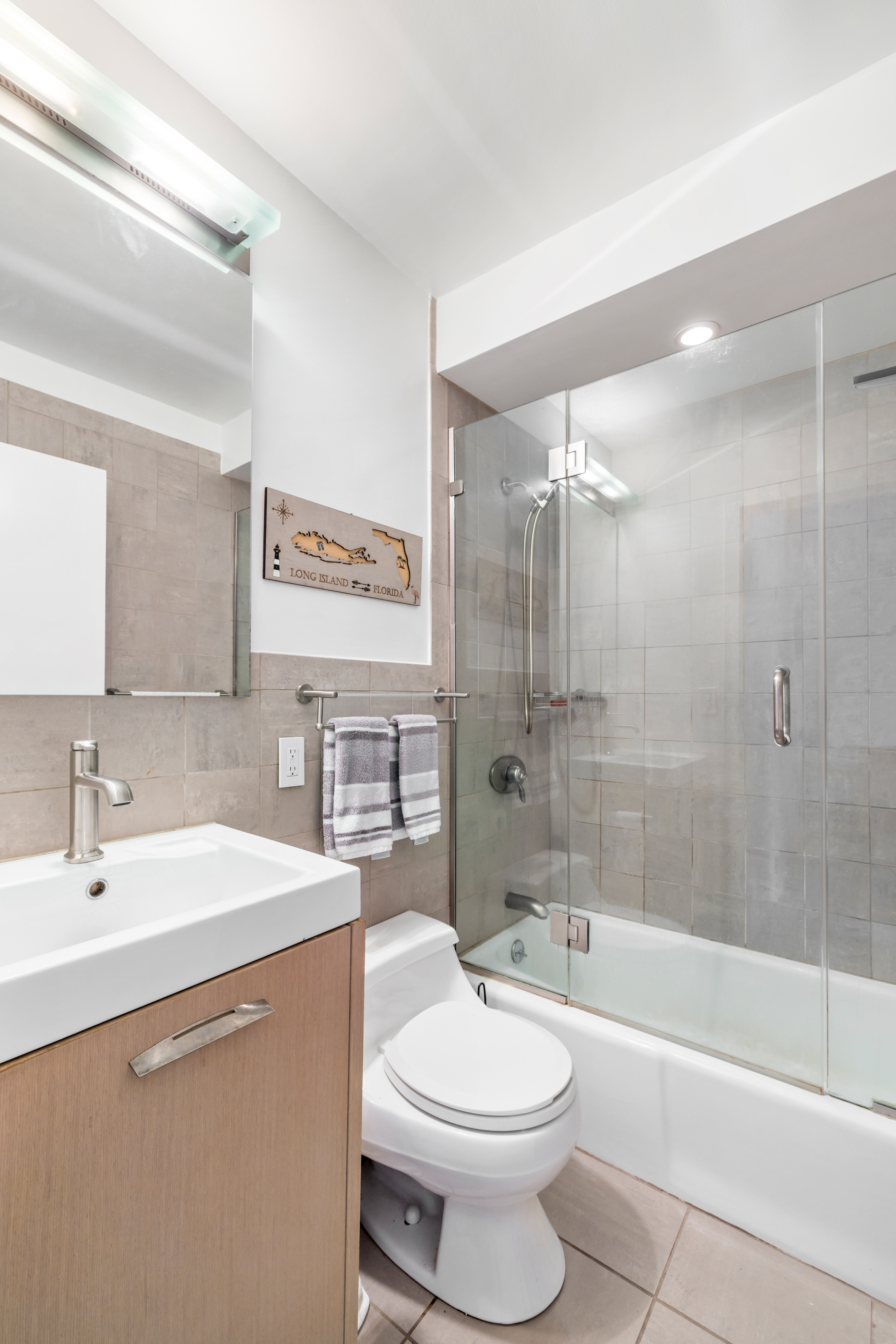 300 East 54th Street, Unit 23E Manhattan, NY 10022 - Photo 9 of 13 a bathroom with a toilet a sink a mirror a bathtub and shower