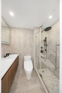 a bathroom with a granite countertop sink a toilet a mirror and shower