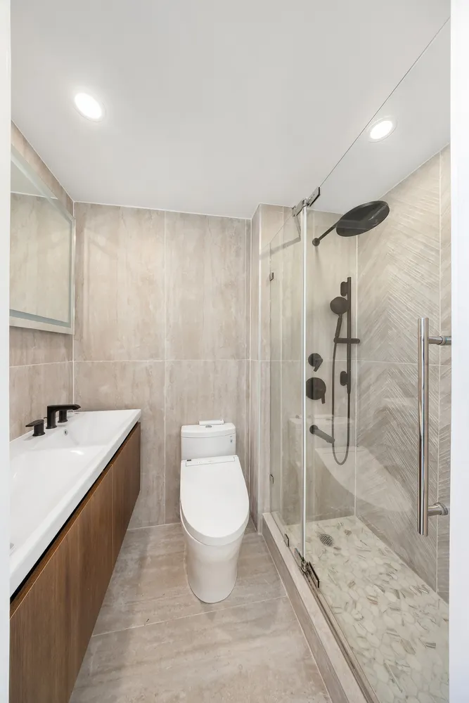 a bathroom with a granite countertop sink a toilet a mirror and shower
