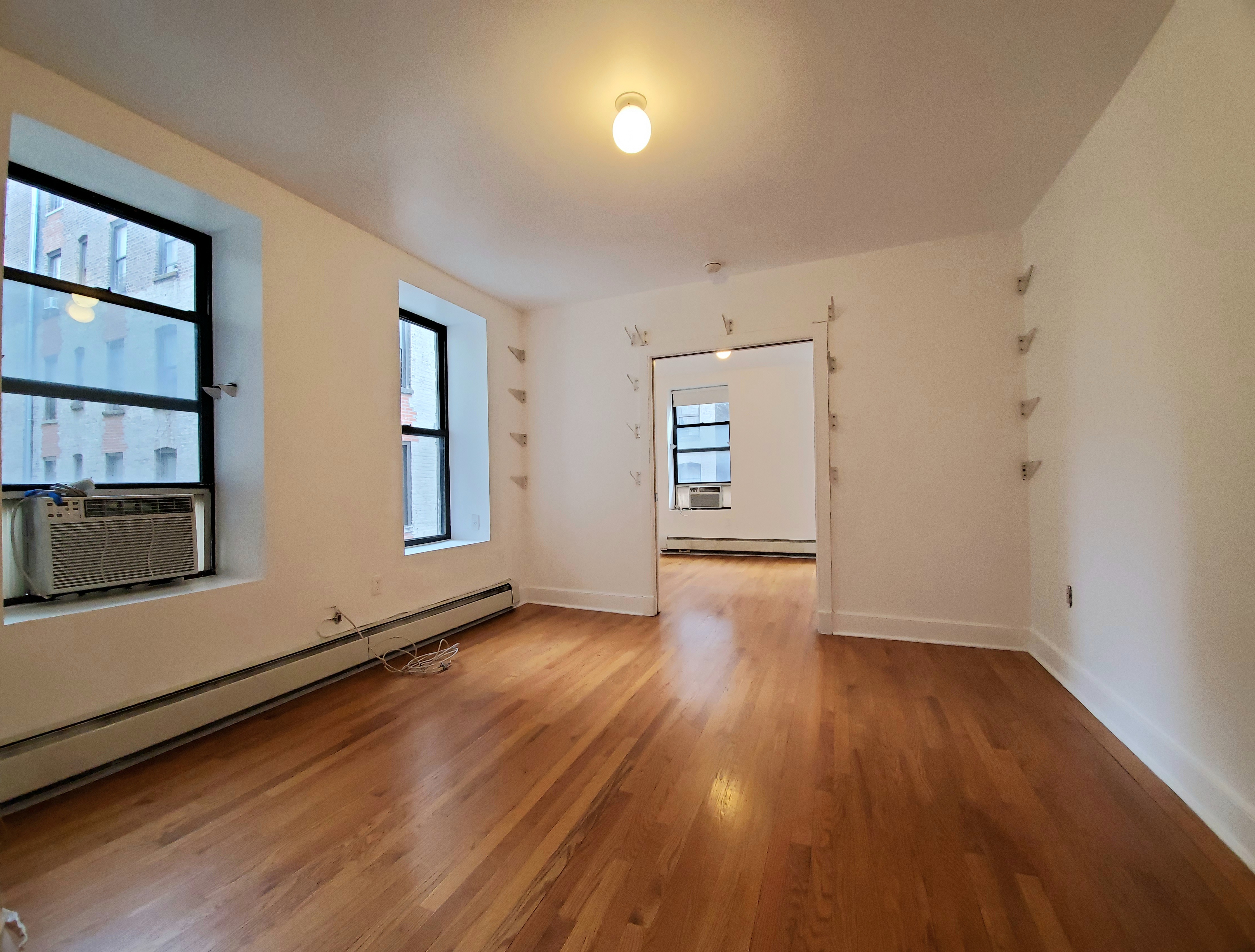 305 West 150th Street, Unit 307 Manhattan, NY 10039 - Photo 4 of 7 an empty room with wooden floor and windows