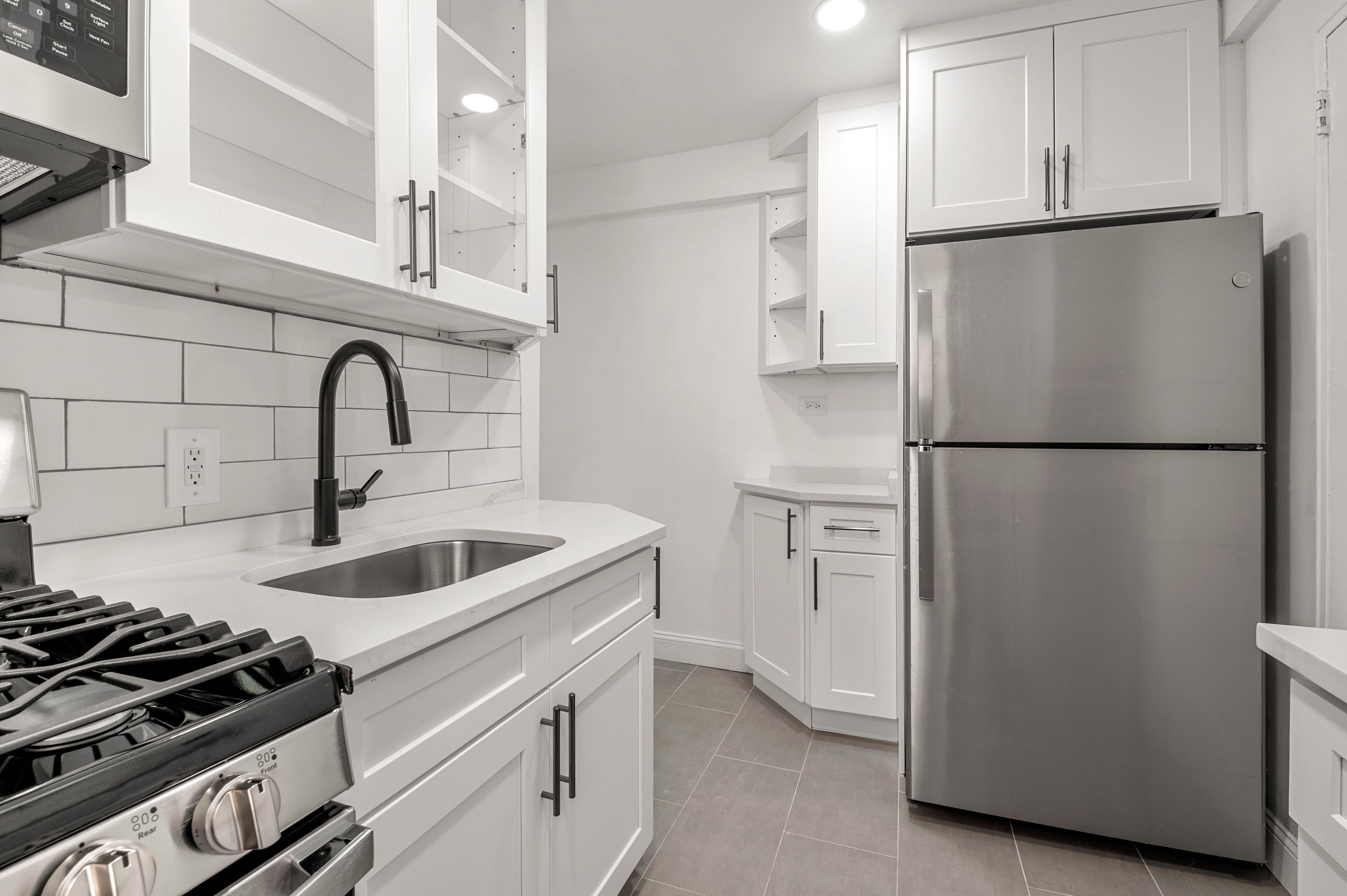65-15 38th Avenue, Unit 1G Queens, NY 11377 - Photo 6 of 12 a kitchen with refrigerator a sink and cabinets