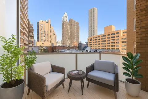 a view of a balcony with chairs and a potted plant