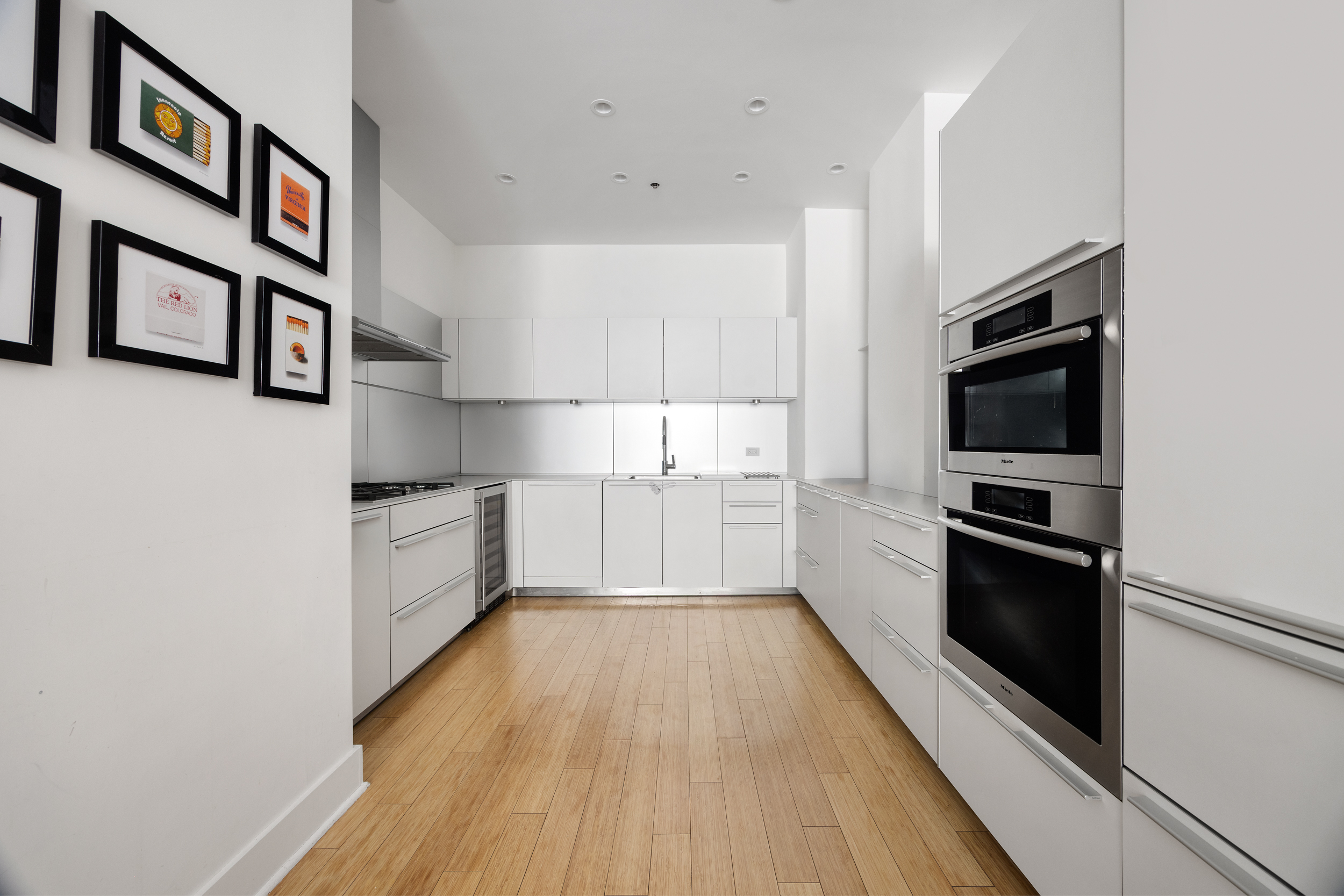 415 Greenwich Street, Unit 5D Manhattan, NY 10013 - Photo 5 of 16 a kitchen with stainless steel appliances a refrigerator and a wooden floor
