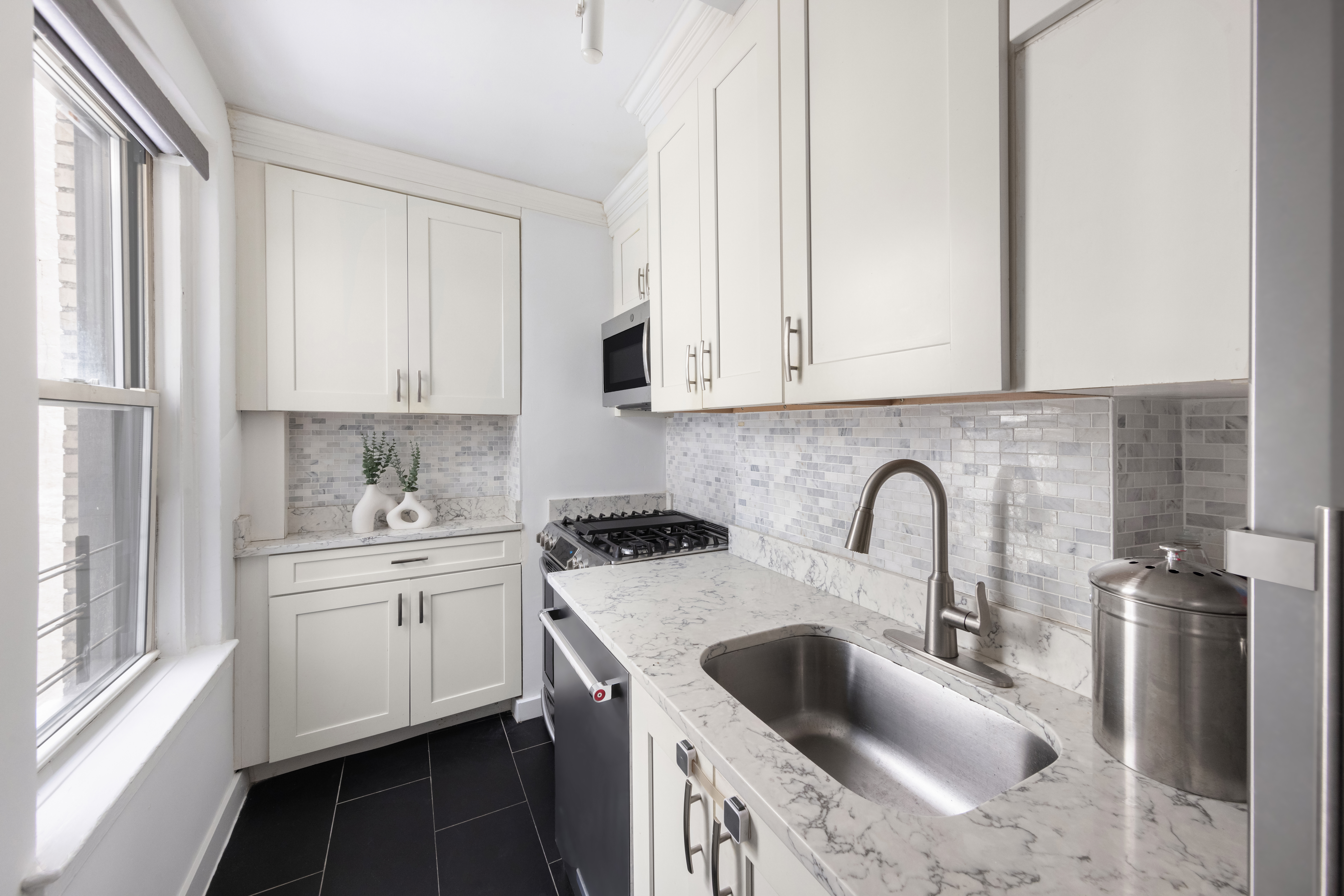 425 East 86th Street, Unit 2F Manhattan, NY 10028 - Photo 4 of 11 a kitchen with stainless steel appliances granite countertop a sink stove and white cabinets