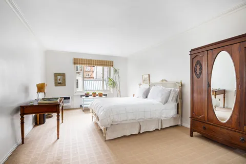 a spacious bedroom with a bed a mirror and a window