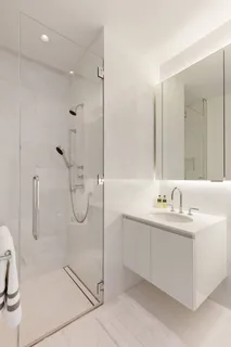 a bathroom with a double vanity sink a toilet and shower
