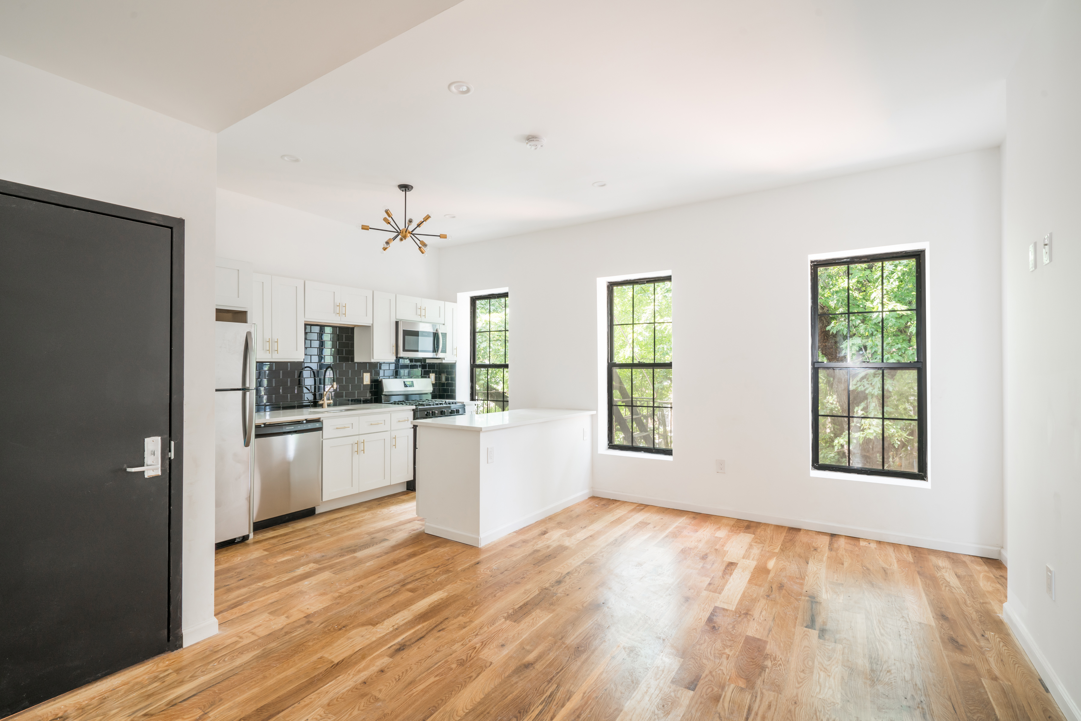a kitchen with stainless steel appliances a refrigerator a sink dishwasher a stove with white cabinets and wooden floor