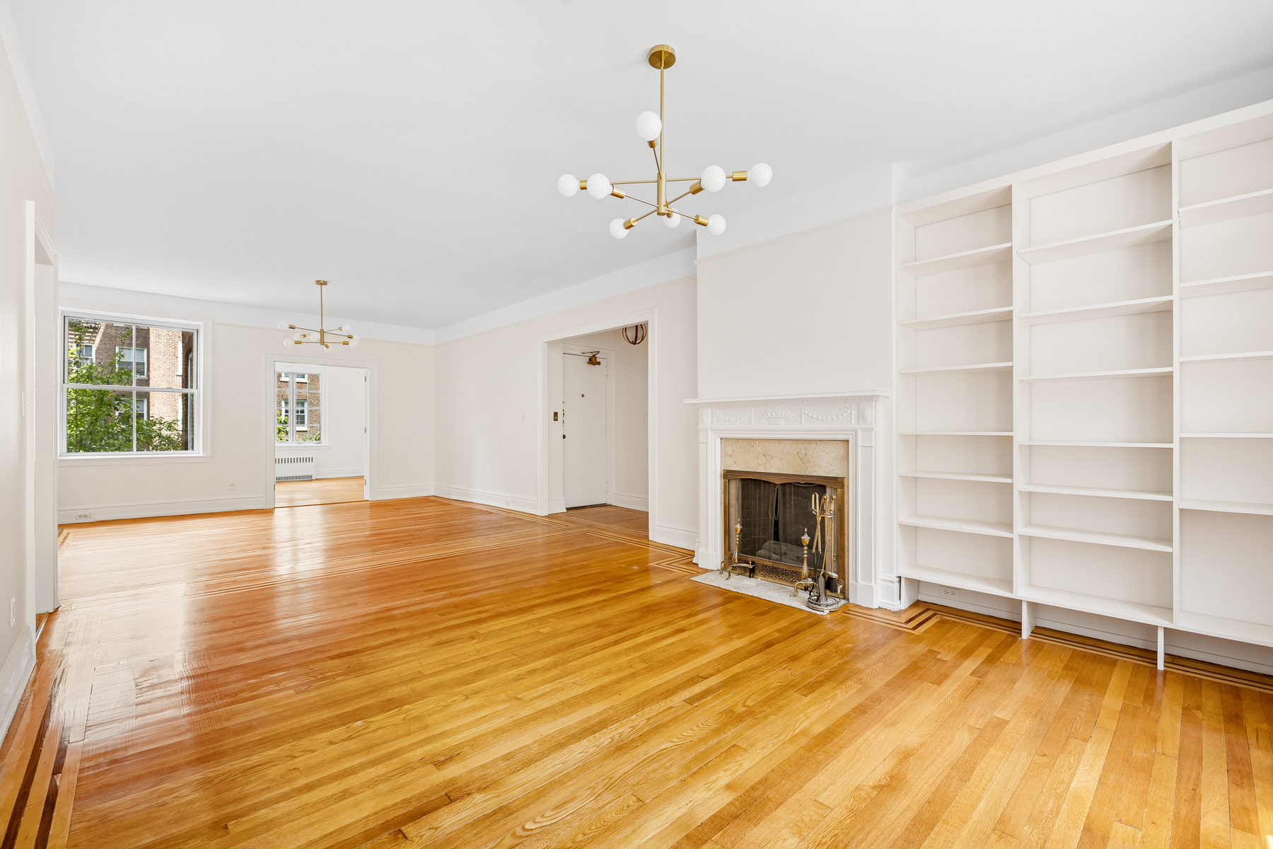 35-27 76th Street, Unit 21 Queens, NY 11372 - Photo 4 of 24 a view of a livingroom with a fireplace a chandelier and wooden floor