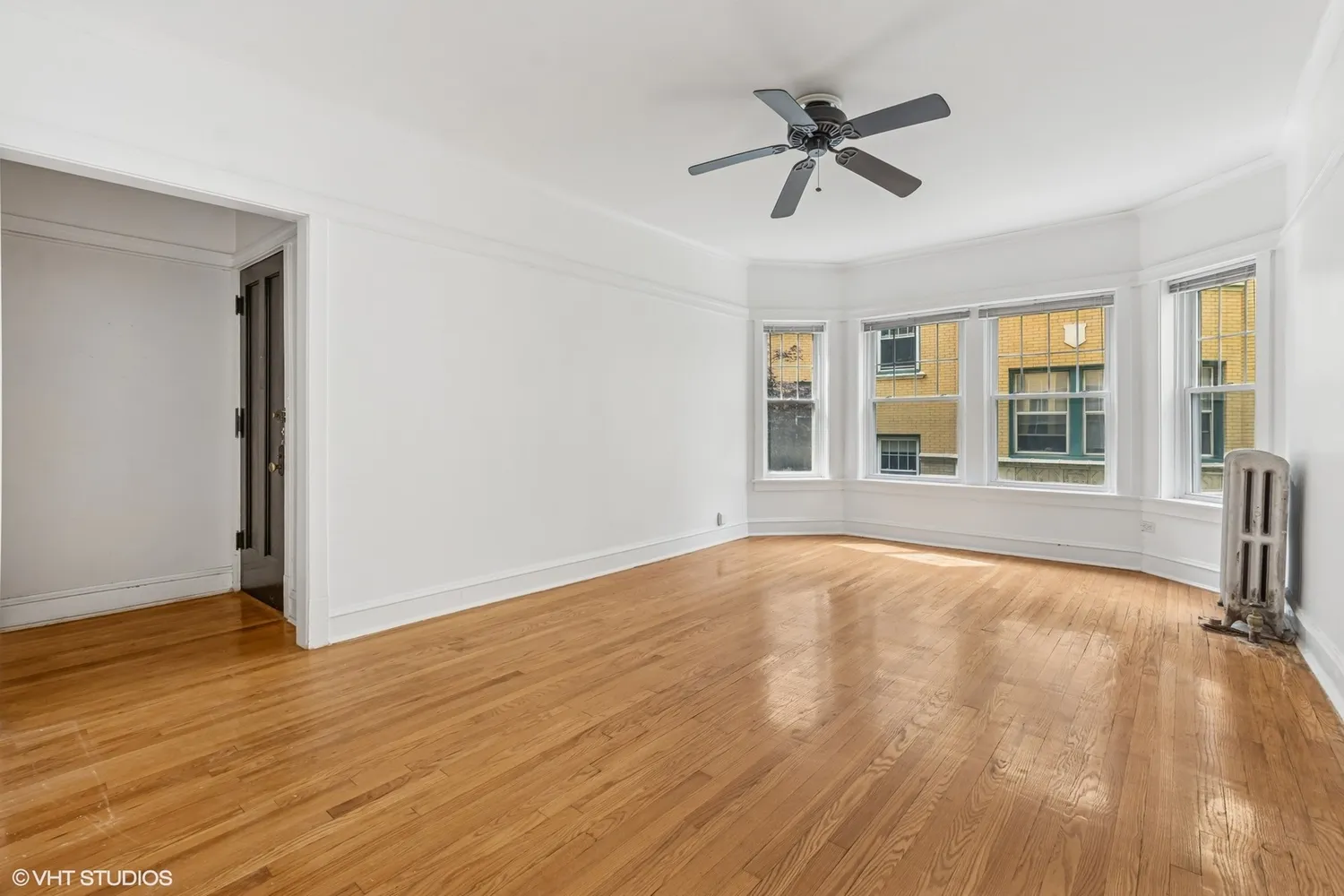 a view of an empty room with wooden floor and a window