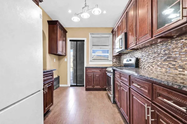 a kitchen with stainless steel appliances granite countertop a refrigerator a stove and a wooden cabinets