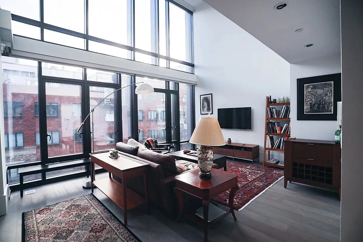 a living room with furniture a rug potted plant and a large window
