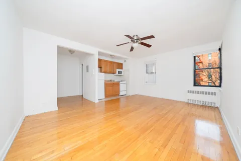 a view of empty room with wooden floor and ceiling fan