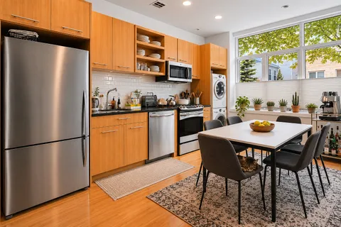 a kitchen with stainless steel appliances granite countertop a refrigerator a stove a sink dishwasher a dining table and chairs with wooden floor