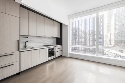 a large white kitchen with granite countertop a large window and white cabinets