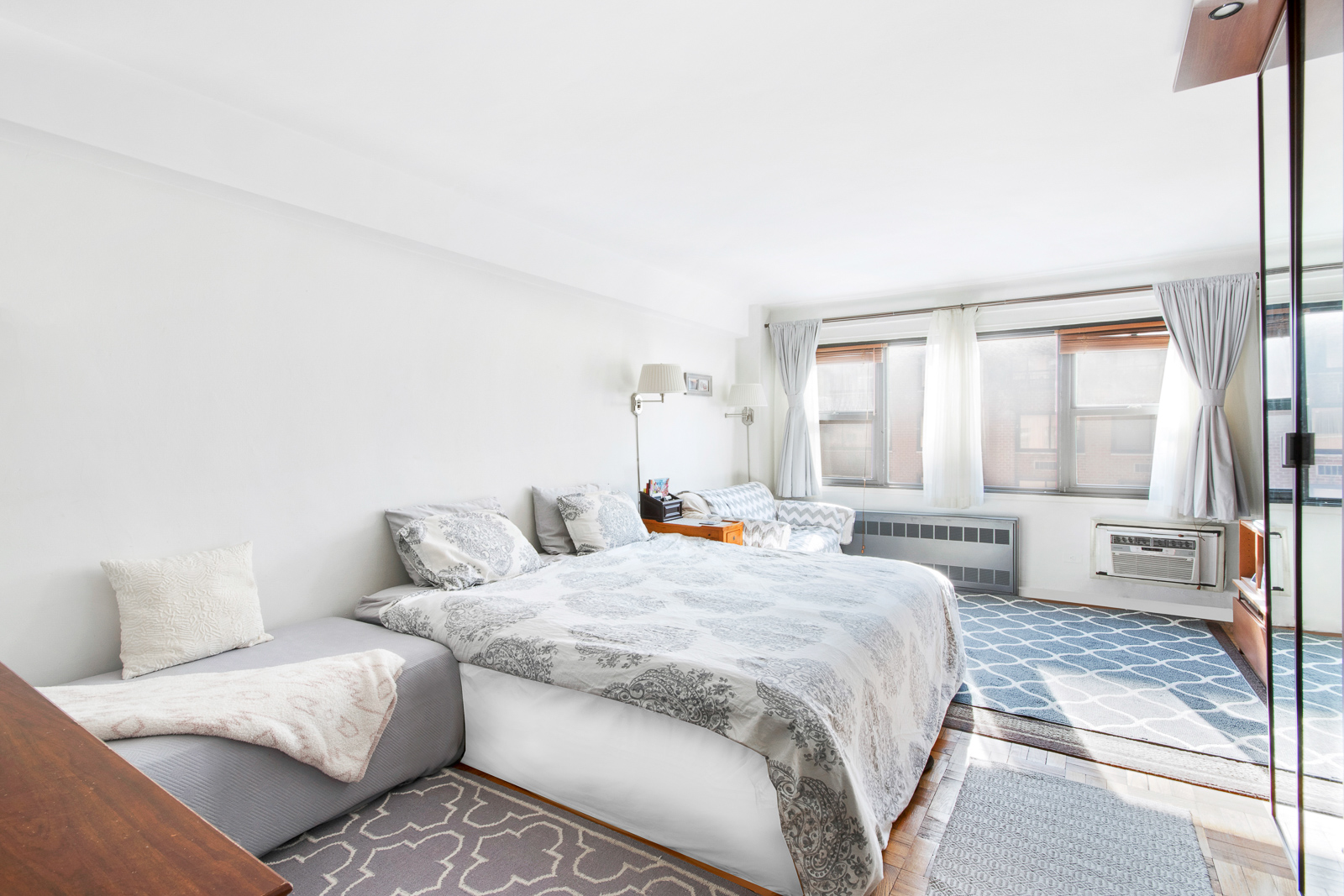 335 East 51st Street, Unit 10C Manhattan, NY 10022 - Photo 1 of 9 a bedroom with a large bed and a couch