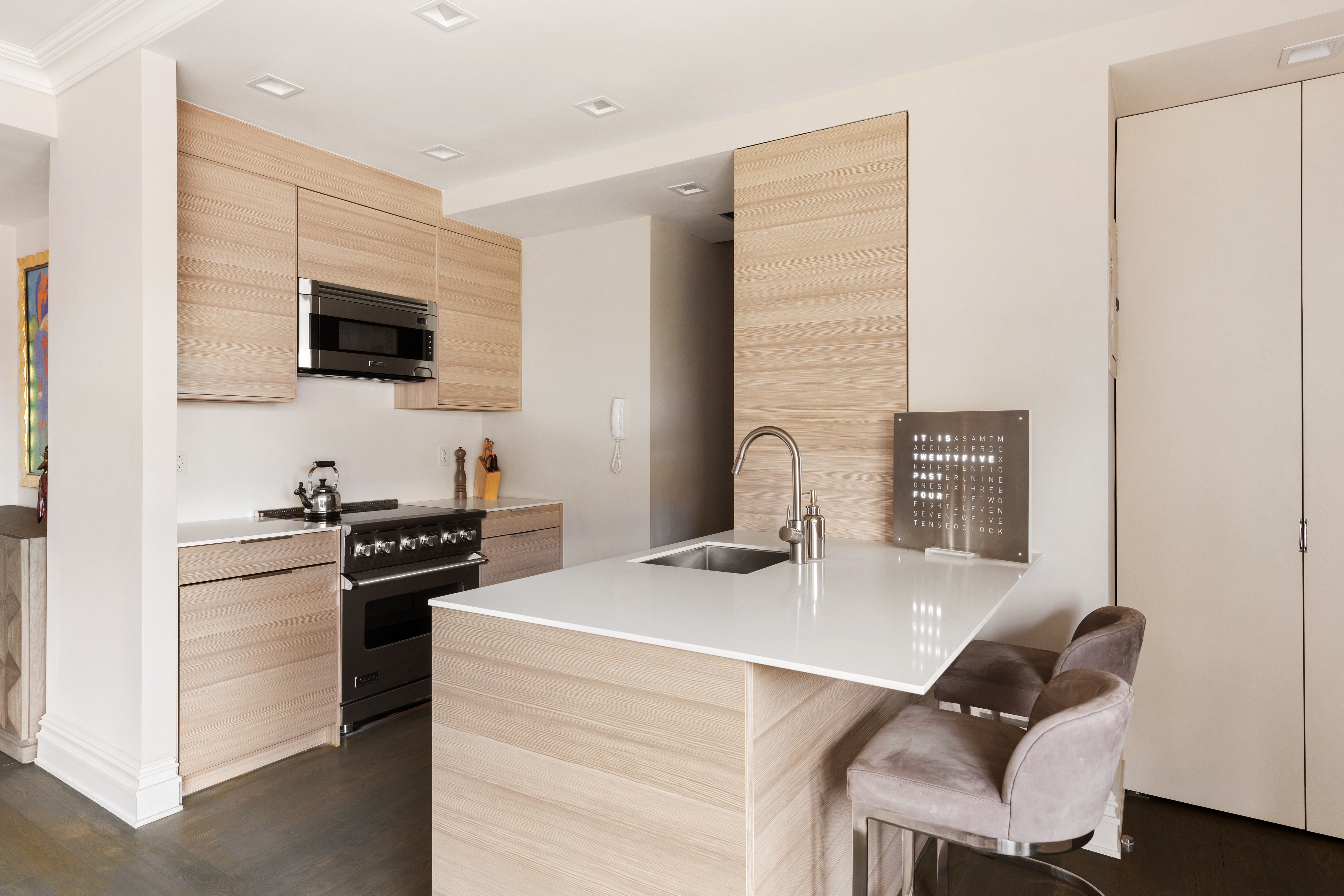 25 East 83rd Street, Unit 10D Manhattan, NY 10028 - Photo 6 of 17 a kitchen with stainless steel appliances kitchen island granite countertop a stove top oven a sink a dining table and chairs with wooden floor