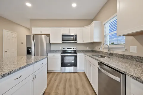a kitchen with granite countertop a refrigerator stove top oven and sink