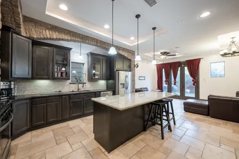 a kitchen with stainless steel appliances granite countertop a kitchen island a stove a refrigerator a oven and a sink