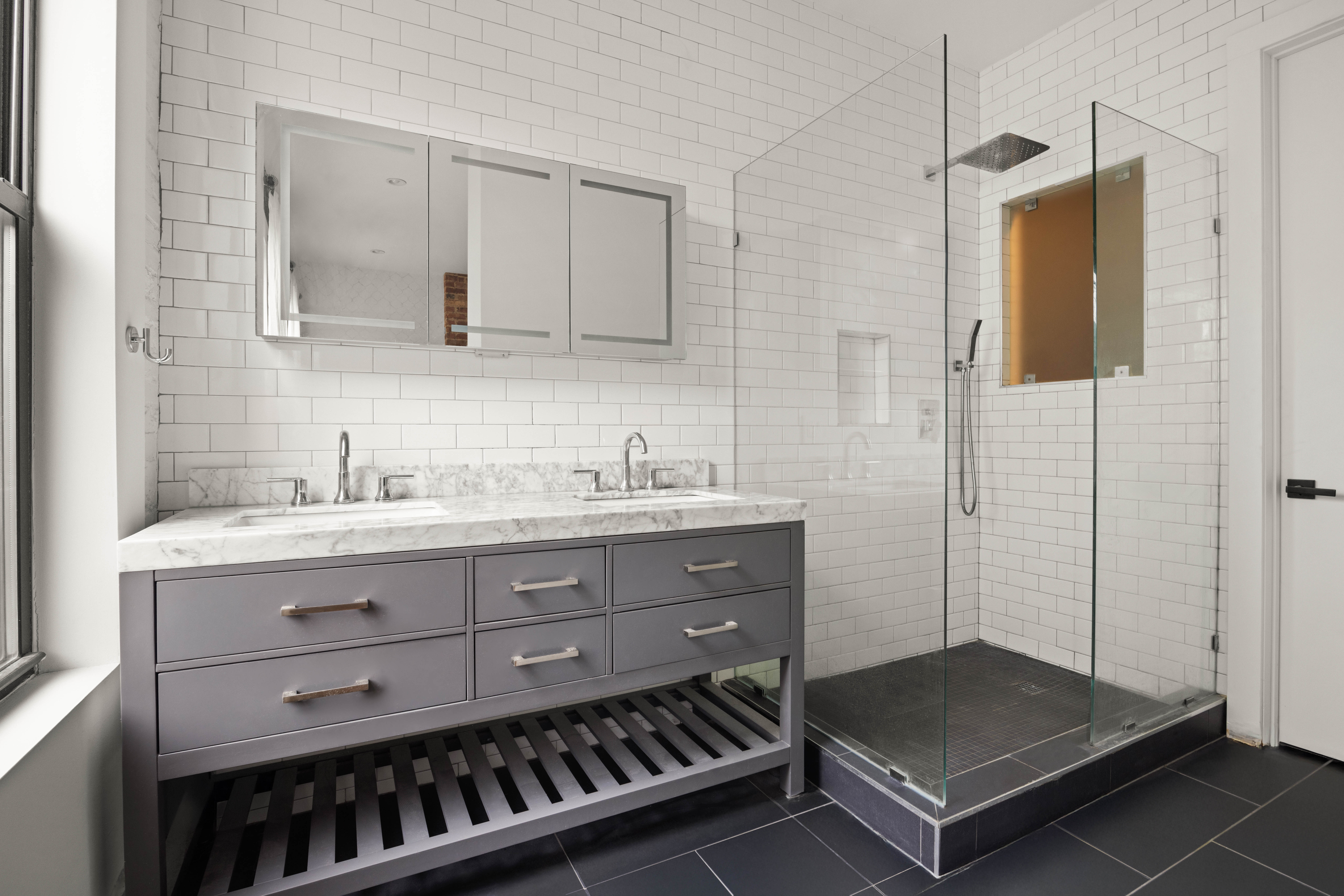 750 Lincoln Place Brooklyn, NY 11216 - Photo 16 of 24 a bathroom with a sink a light fixture and a glass door shower