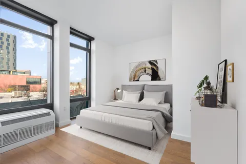 a bedroom with a bed and a large mirror next to a window