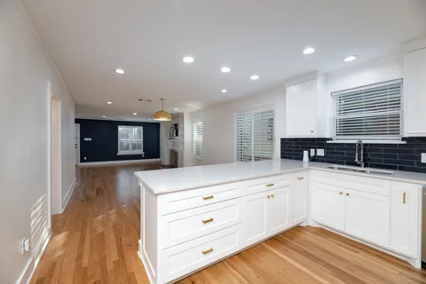 a kitchen with stainless steel appliances granite countertop a sink and white cabinets with wooden floor