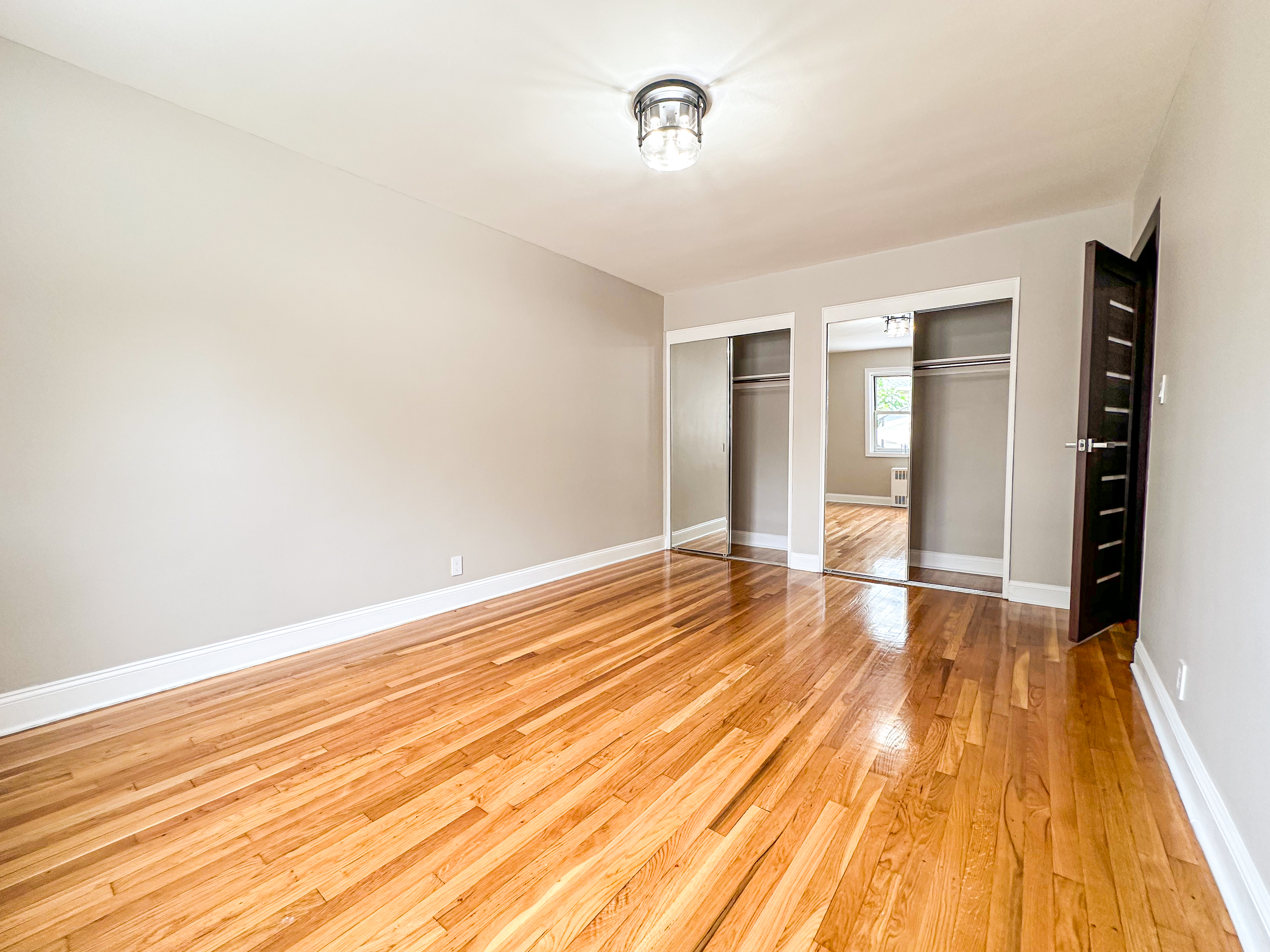 10-01 154th Street, Unit 1 Queens, NY 11357 - Photo 6 of 10 an empty room with wooden floor and windows