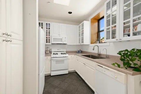 a kitchen with granite countertop white cabinets and white appliances