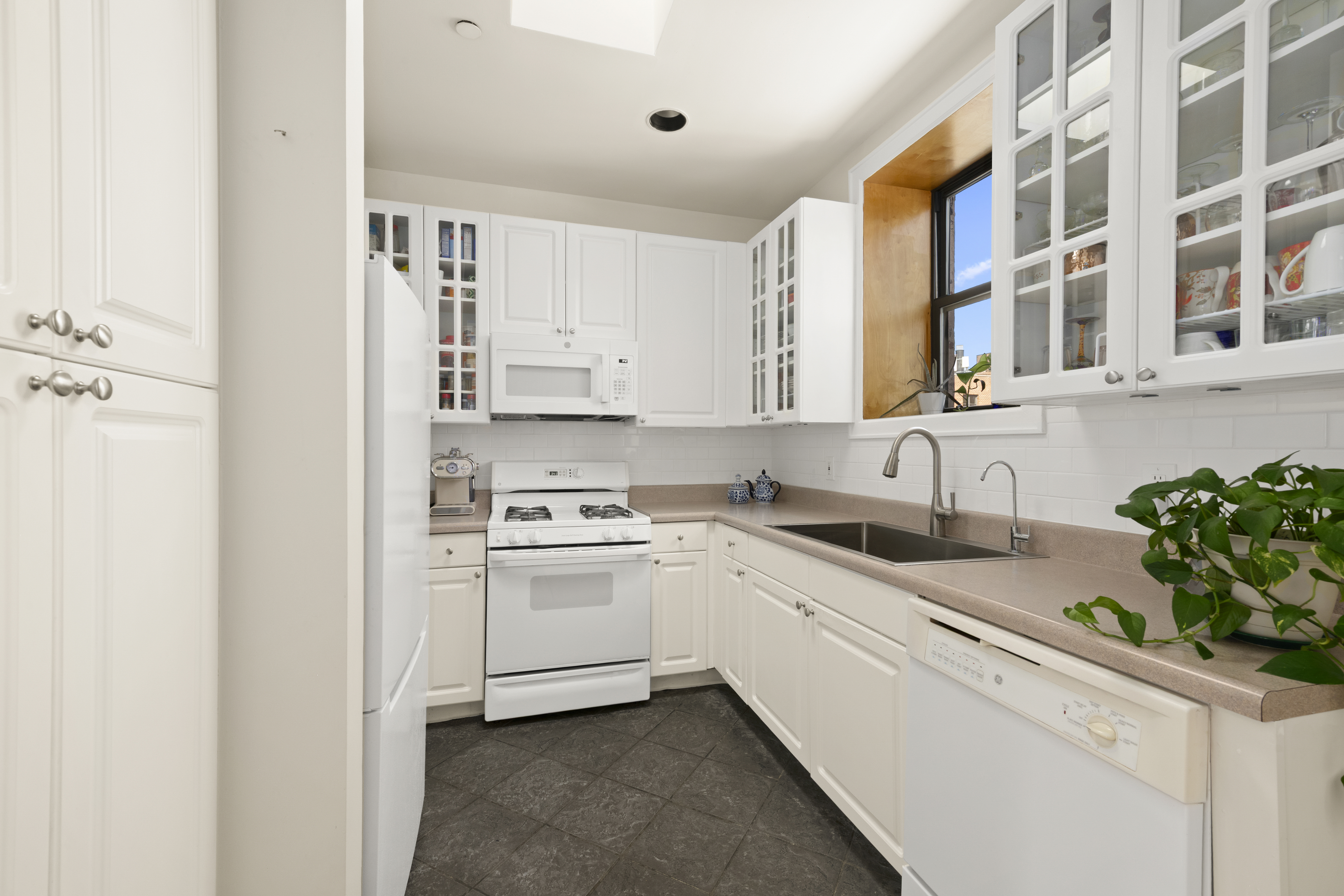 370 St Nicholas Avenue, Unit PH5B Manhattan, NY 10027 - Photo 5 of 12 a kitchen with granite countertop white cabinets and white appliances