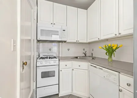 a kitchen with granite countertop white cabinets and white appliances