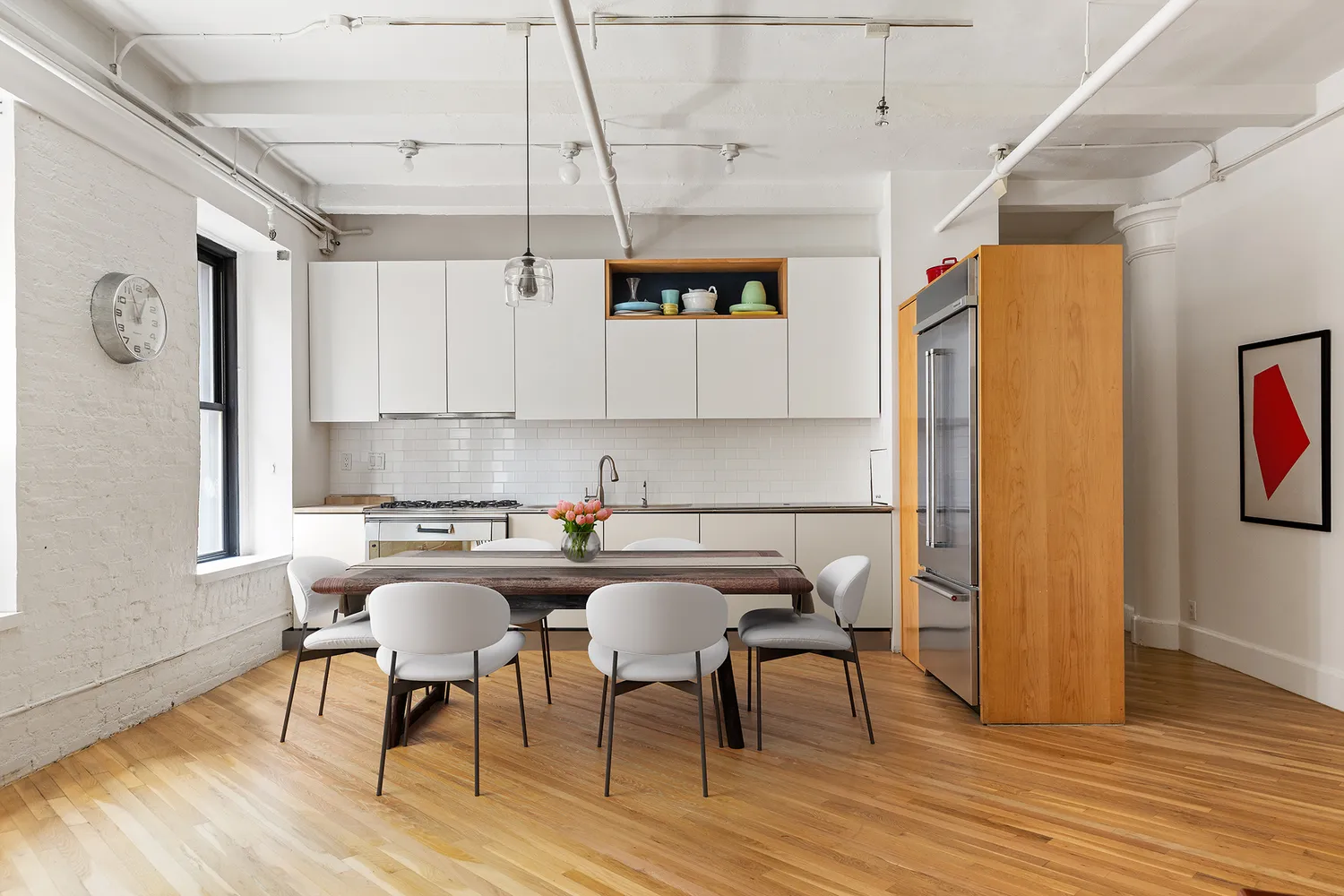 a kitchen with stainless steel appliances granite countertop a dining table chairs refrigerator and sink