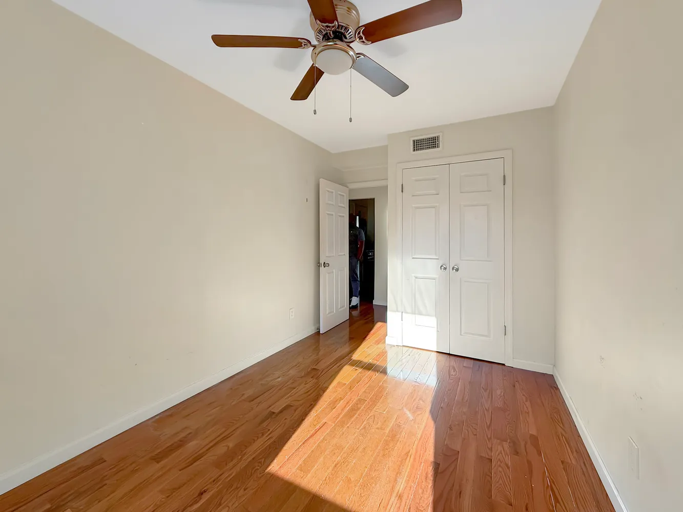 a view of a room with wooden floor and a ceiling fan