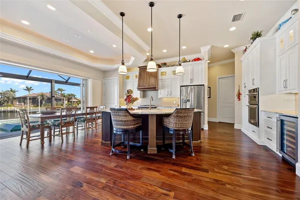 a view of a dining room and livingroom with furniture wooden floor kitchen chandelier