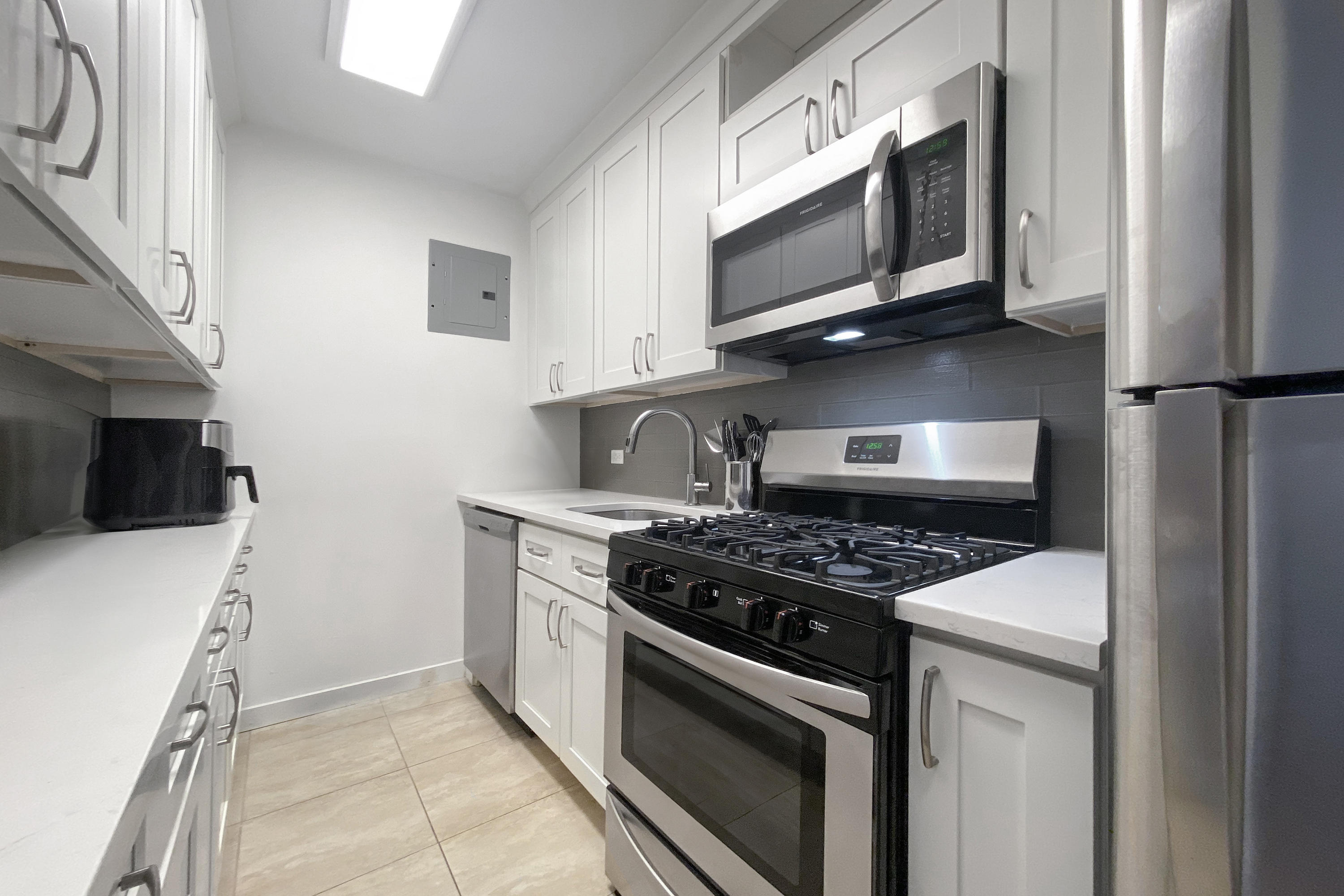 300 East 33rd Street, Unit 10A Manhattan, NY 10016 - Photo 3 of 14 a kitchen with stainless steel appliances a stove a microwave and cabinets