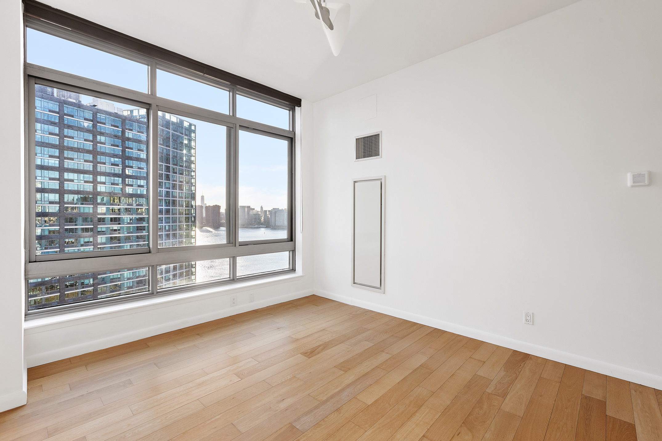 46-30 Center Boulevard, Unit PH8 Queens, NY 11109 - Photo 11 of 32 a view of empty room with wooden floor and fan
